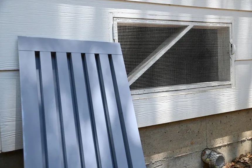 Vent covering with ember-resistant mesh installed over a crawlspace vent